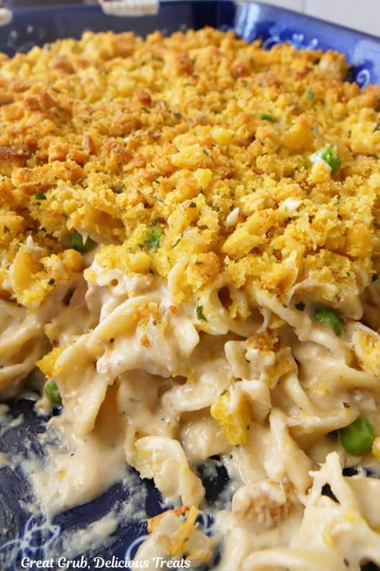 A blue baking dish with tuna noodle casserole in it with some scooped out.