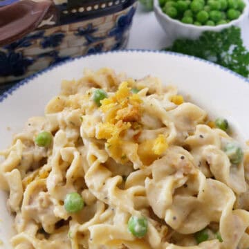 A white bowl with blue trim filled with a serving of old fashioned tuna noodle casserole.