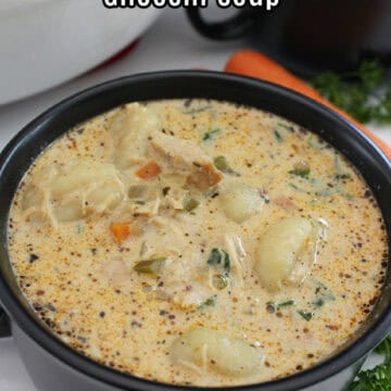 A black soup bowl with handles filled with homemade chicken gnocchi soup.