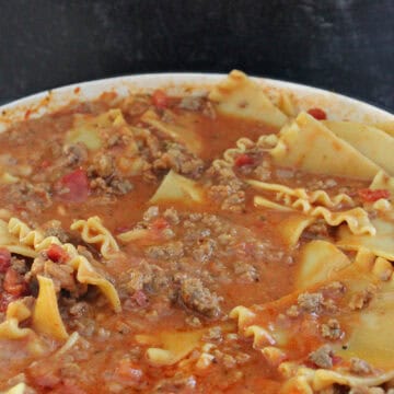 A white cast iron pot filled with lasagna soup, with the title of the recipe in text at the top.