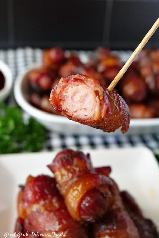 A close up of a little smokie on a toothpick with a bite taken out of the little smokie.