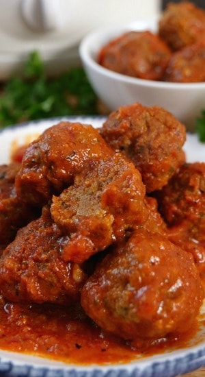 Homemade Italian Meatballs are savory, full of flavor and are scrumptious. A white plate with blue trim with a small stack of meatballs on it.
