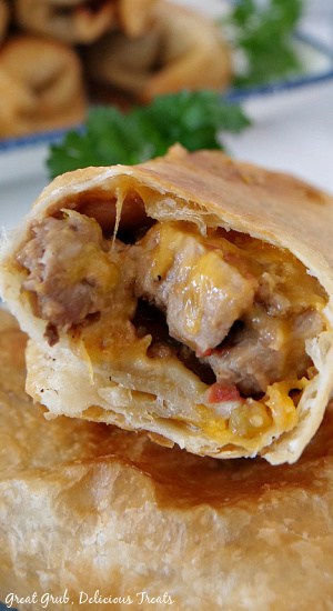 Fried Burritos are full of delicious flavors of tender pork and beef, hamburger, beans, green chilies, cheese and then fried to a golden perfection. A close up photo of a fried burrito and the filling inside.