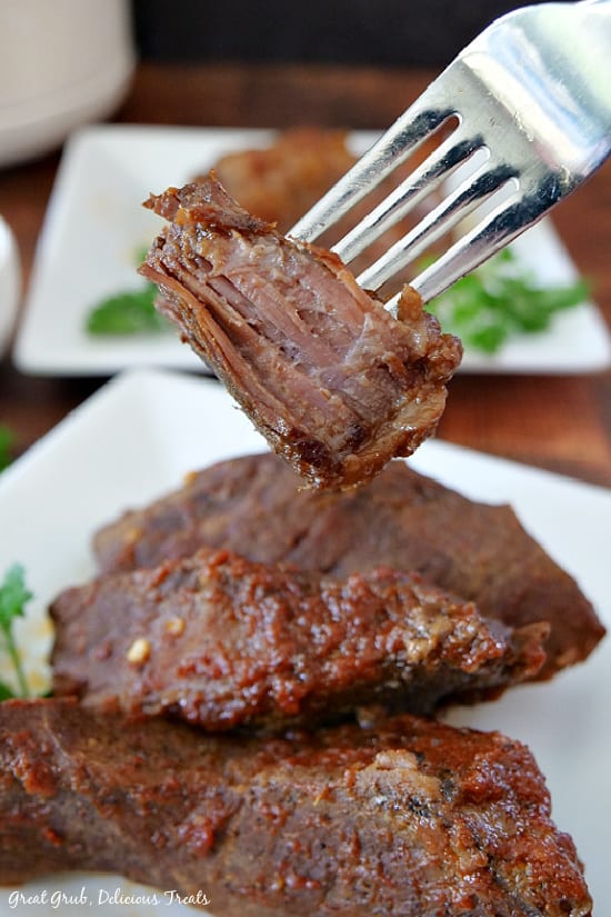 Crock Pot Texas Style Boneless Beef Ribs are deliciously seasoned, slow cooked in a homemade barbecue sauce and are so tender. Crock Pot Texas Style Boneless Beef Ribs on a white plate with a fork holding up a bite of meat.