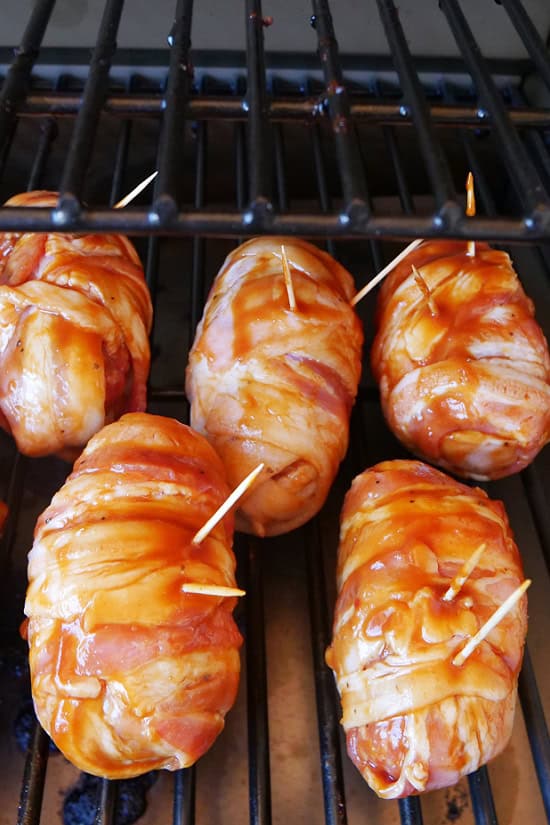 Armadillo eggs place on the grills of the smoker with BBQ sauce basted over them.