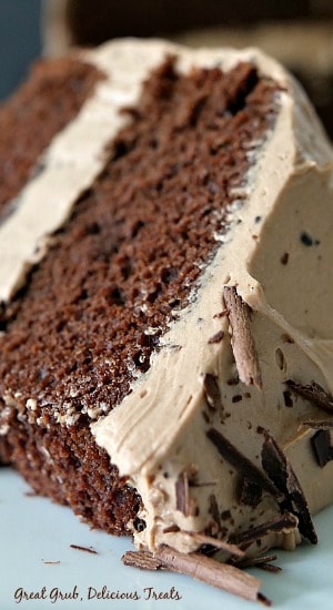 Chocolate Cake with Mocha Mascarpone Frosting is moist, delicious, and has a scrumptious mascarpone frosting. #cakerecipe #chocolatelayercake #easycakerecipe #moistchocolatecake #greatgrubdelicioustreats A close up of a slice of chocolate cake laying on a white plate.