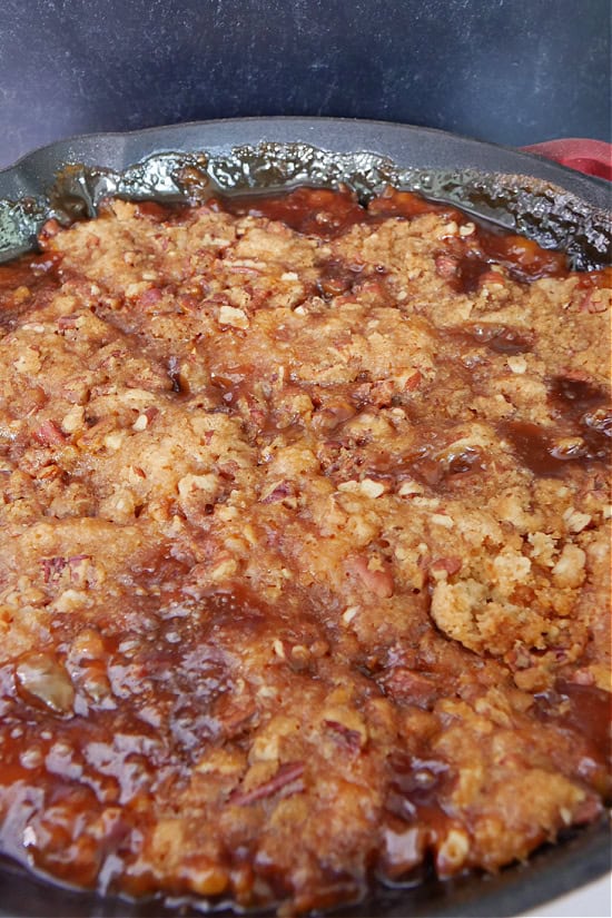 A cast iron pan with a smoked peach cobbler in it.