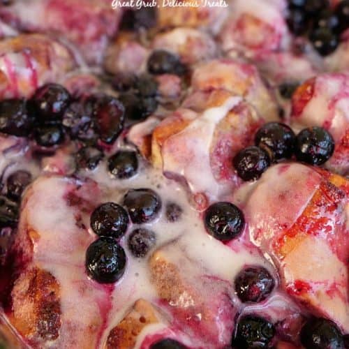 Cinnamon rolls topped with blueberries in a baking dish.