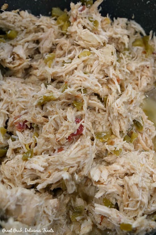 Crock Pot Spicy Chicken is the perfect base recipe to use when making chicken tacos, chicken flautas or even chicken enchiladas. Crock Pot Spicy Chicken - shredded chicken in the crock pot that shows the shredded chicken, diced jalapenos and tomatoes.