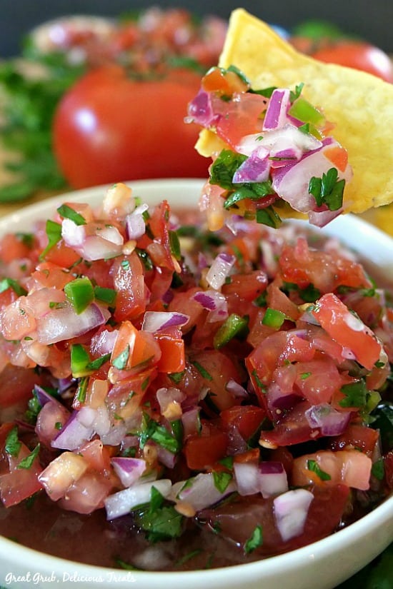 Pico de Gallo is a delicious salsa dip recipe loaded with flavor and the freshest ingredients. Pico de Gallo - a white bowl full of homemade salsa with some chunky salsa on a tortilla chip.