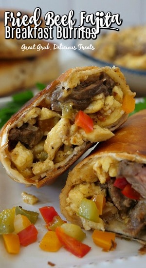 A close up photo of a beef fajita breakfast burrito, cut in half showing the ingredients, on a white plate.