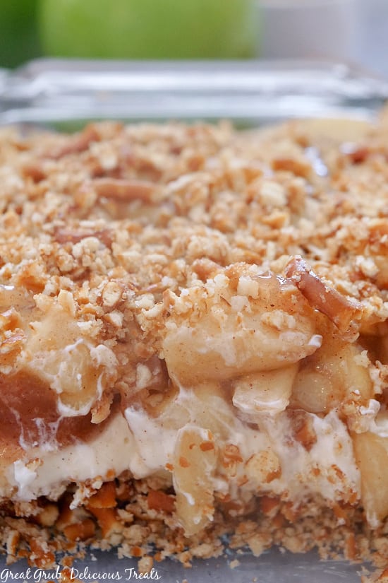 Apple Cinnamon Pretzel Salad is a crunchy, creamy, delicious layered apple dessert recipe. A close up view of Apple Cinnamon Pretzel Salad in a 9 x 13 baking dish with some of the dessert removed showing the layers of the dessert.