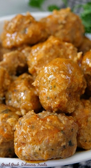 Buffalo Turkey Meatballs are sow cooked in buffalo sauce and packed full of delicious flavors that will sure be a hit at any party. A white bowl full of 12 buffalo turkey meatballs with parsley in the background for decoration.