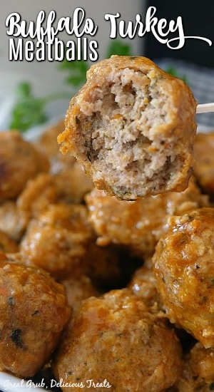 Buffalo Turkey Meatballs are a ground turkey recipe that are super flavorful, slow cooked in buffalo sauce, and a great addition to any party snack table. A white bowl of buffalo turkey meatballs with one meatball on a toothpick with a bite taken out of it.
