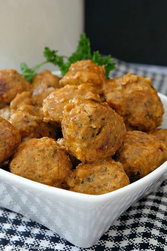 Buffalo Turkey Meatballs are a quick and easy appetizer packed full of flavor and the perfect amount of spice. Turkey meatballs in a small white bowl with a plaid placemat underneath with parsley for decoration in the background.