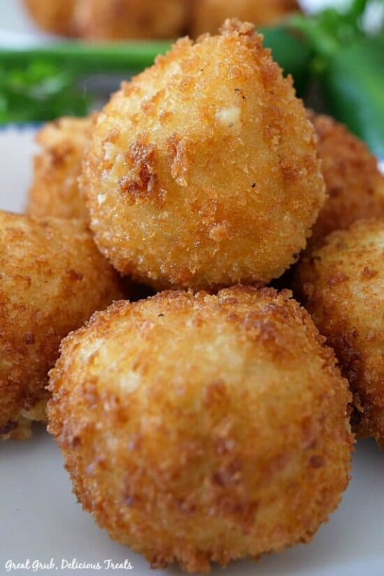 Loaded Mashed Potato Balls are a great appetizer to take to any party or a great side to make instead of traditional mashed potatoes. Mashed potato bites on a white plate with parsley in the background.