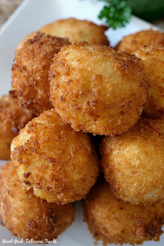 Loaded Mashed Potato Bites are loaded with delicious flavor, crunchy on the outside and are the perfect appetizer recipe for holiday dinner, pot lucks, and family gatherings. A white plate with about 10 loaded mashed potato bites.