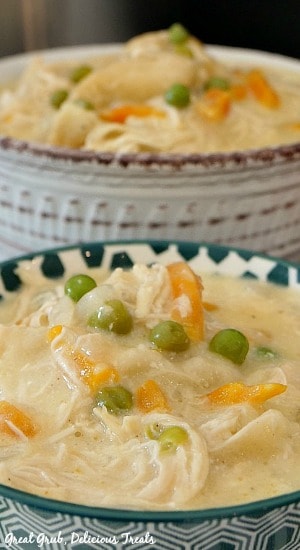 Crock Pot Chicken and Dumplings is a simple crock pot recipe that is the perfect meal for any night of the week. Zoomed in photo of chicken and dumplings in a teal and white spotted bowl with another bowl full of chicken and dumplings in the background.