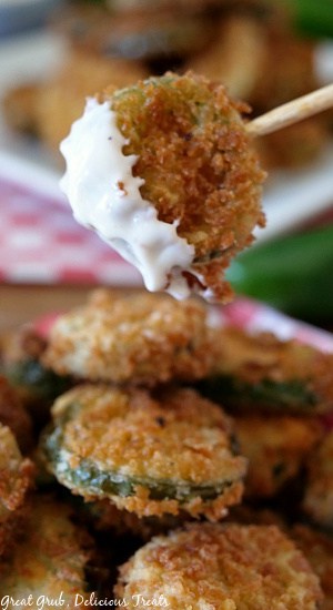 Deep Fried Crispy Jalapenos are super delicious, are coated in a delicious batter, fried to perfection and a favorite fried jalapeño recipe. A close up photo of fried jalapenos with one on a stick and dipped in ranch dressing.