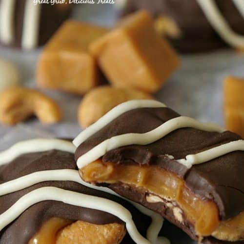 Three cashew clustes with chocolate on parchment paper.