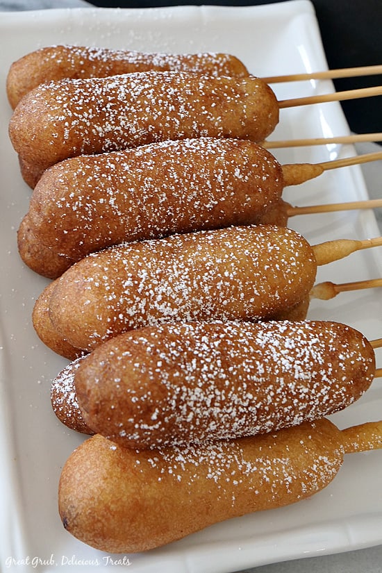 Pancake Sausage on a Stick makes an easy, grab and go, breakfast recipe that everyone will enjoy. 10 pancake sausage on a stick dusted with powdered sugar placed on a white oblong plate