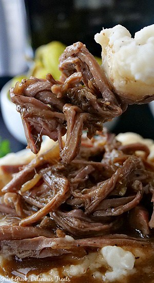 A close up photo of a bite of Mississippi pot toast and mashed potatoes on a fork.