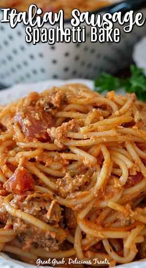 Italian Sausage Spaghetti Bake is a delicious casserole recipe full of flavor, Italian sausage, cheese, pasta and more. Italian Sausage Spaghetti Bake in a white bowl with a black and white polka dot baking dish in the background.