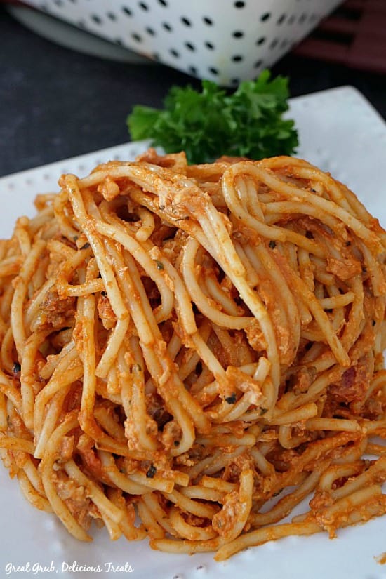 Italian Sausage Spaghetti Bake is a filling and delicious pasta recipe, loaded with Italian sausage, cheese, cream cheese and more. A white plate with Italian Sausage Spaghetti Bake on it with a little curly parsley placed on the plate.