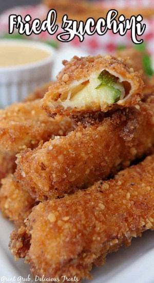 A close up photo of a stack of fried zucchini with a bite taken out of one of them.