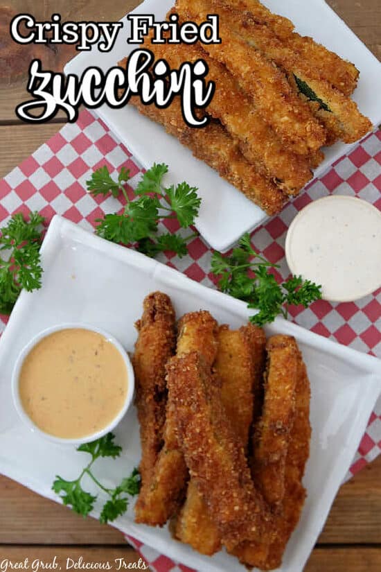 An overhead shot of fried zucchini on white plates with dipping sauces.