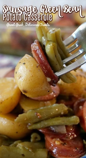 Sausage Green Bean Potato Casserole is loaded with kielbasa, baby creamer potatoes and green beans. A fork with a bite of potato, green beans and a slice of kielbasa on it.