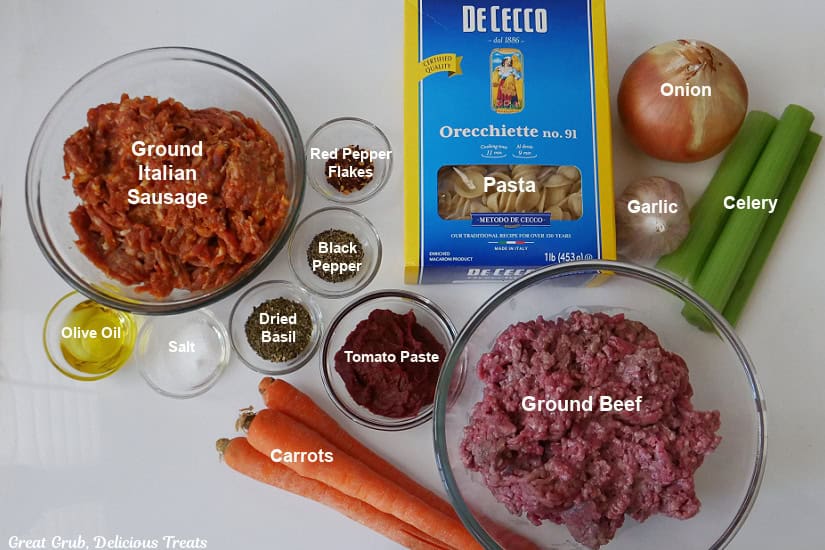 A white surface with clear glass bowls filled with the ingredients for pasta bolognese.