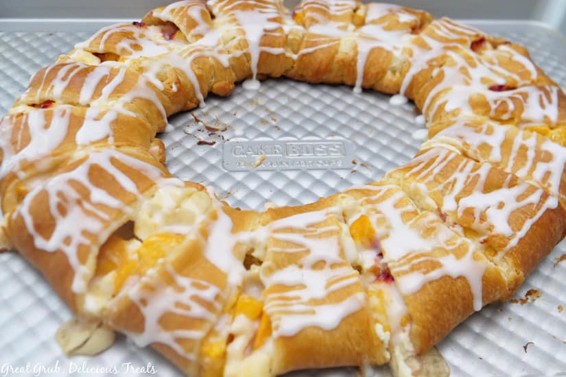 A circle pastry ring on a cookie sheet, covered in a glaze drizzle.
