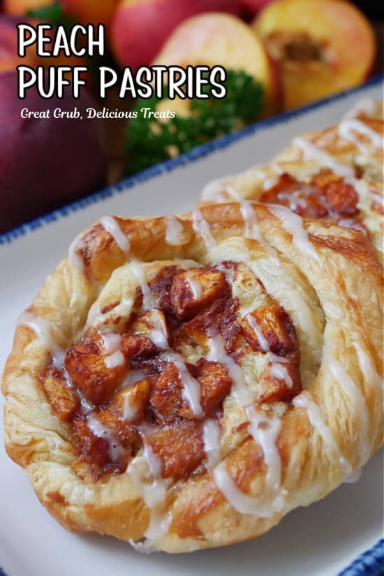 A close up of a couple peach pastries on a white plate with blue trim.