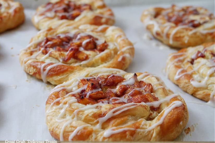 A horizontal photo of pastries on a baking sheet that have been drizzled with glaze.