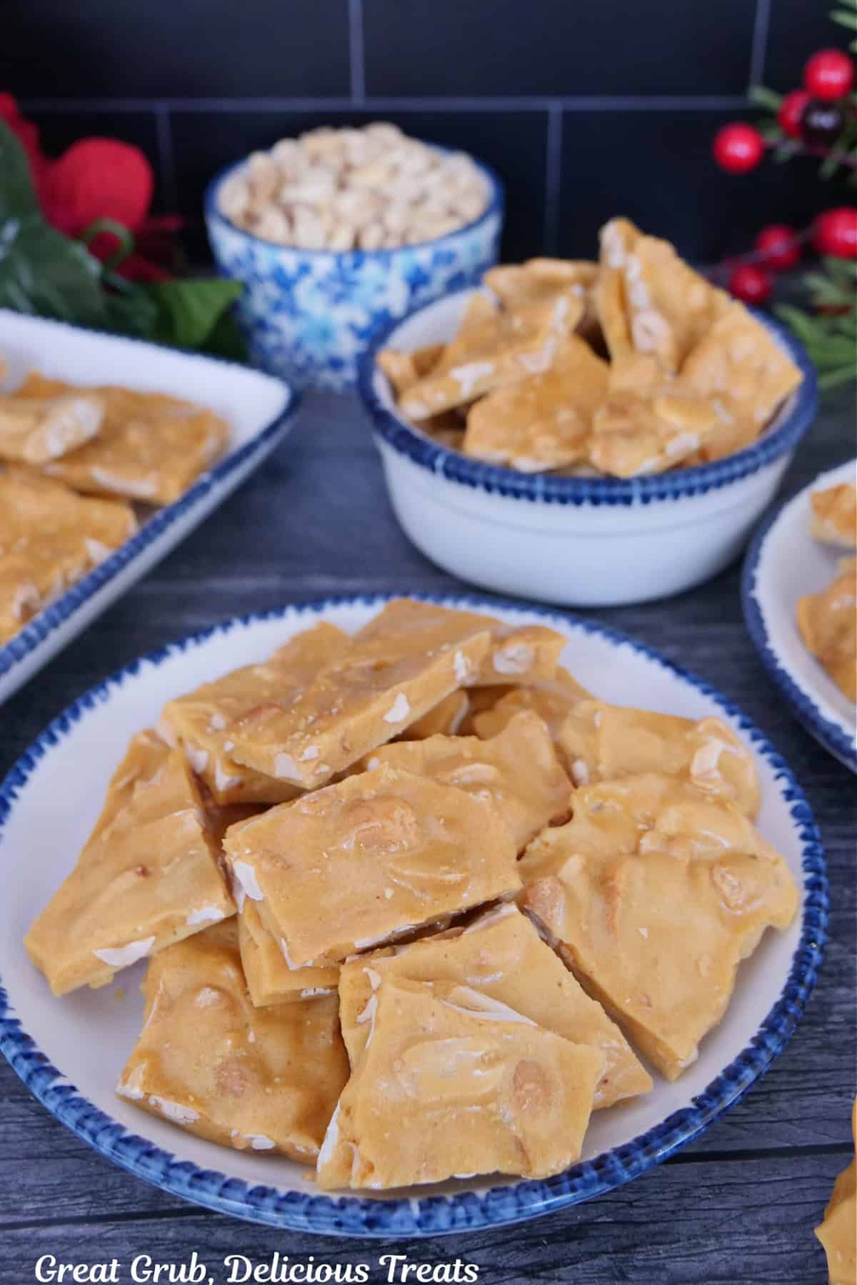 A grey surface with peanut brittle on a few white plate with blue trim.