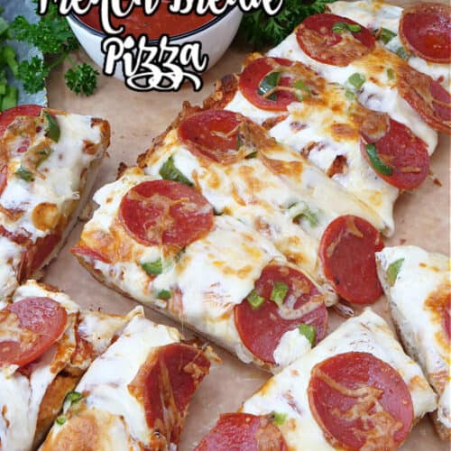 A loaf of French bread pizza on a cutting board.