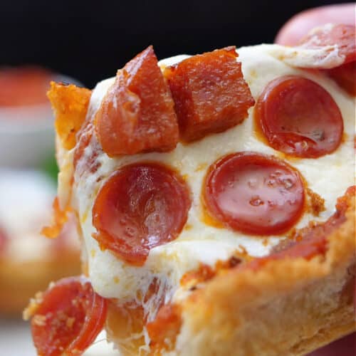 A close up of a slice of French bread pepperoni pizza on a hoagie roll.