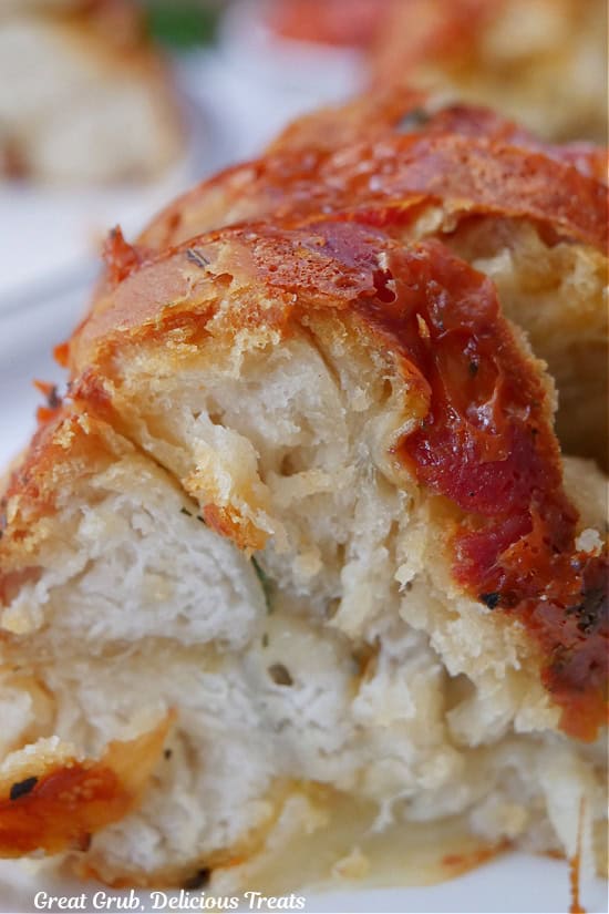 A close up photo of a serving of pepperoni pizza monkey bread on a white plate.