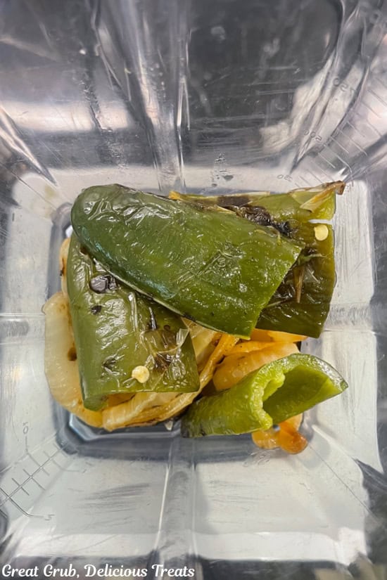 Roasted poblanos, roasted jalapenos and onions are added to a blender.
