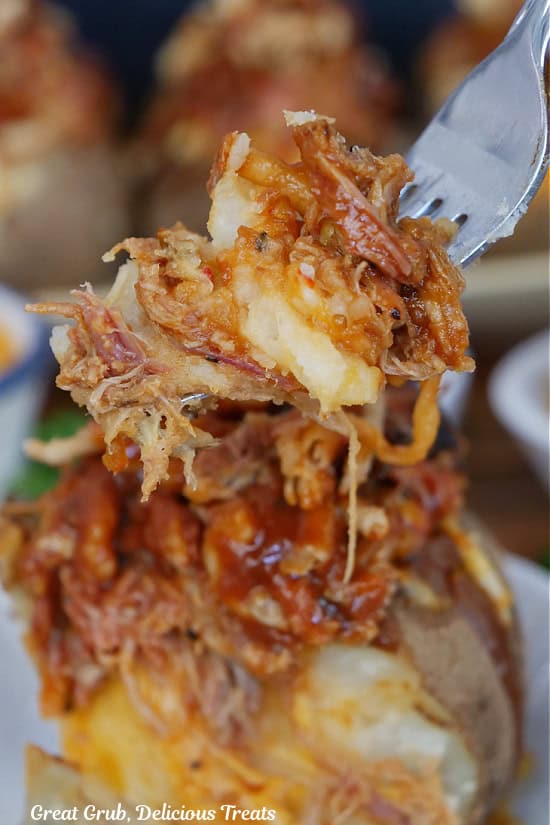 A bite of pulled pork stuffed potato on a fork.