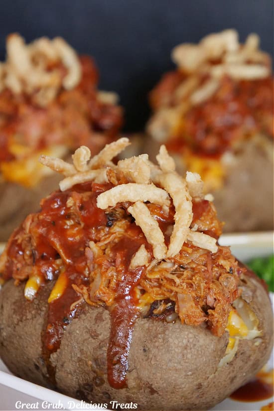 A baked potato stuffed with leftover puller pork with barbecue sauce drizzled over the top and topped with crispy onion strings.