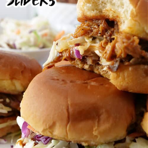 Sliders stacked on a white plate with a bite taken out of the top slider.