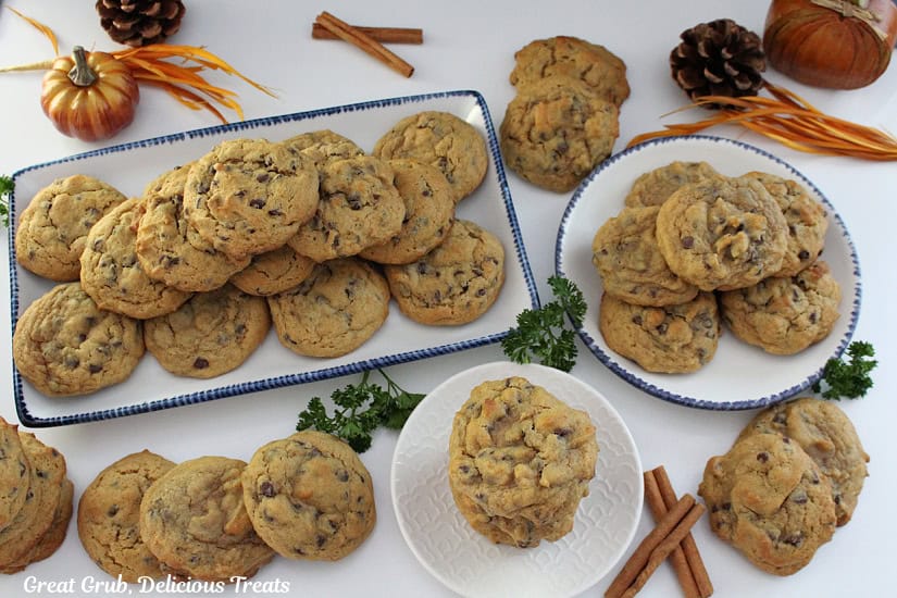 A countertop with pumpkin cookies on it with cinnamon sticks and fall decorations randomly placed.