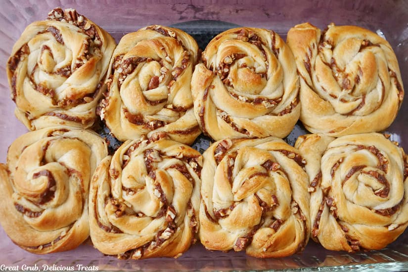 A glass baking dish with eight pumpkin cinnamon rolls in it after being baked.