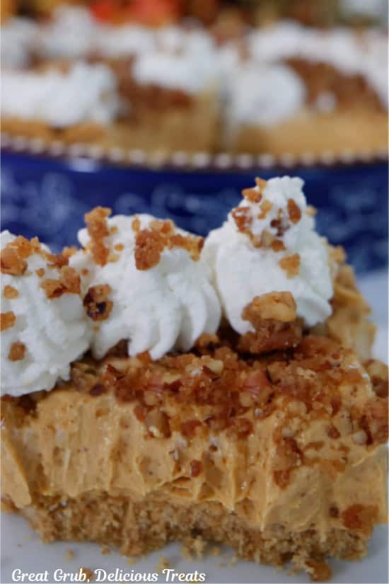 A white surface with a slice of pumpkin spice cream cheese pie on it with a few bites taken.