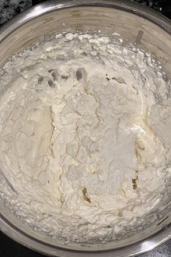 A mixing bowl with homemade whipped cream in it after being whipped.