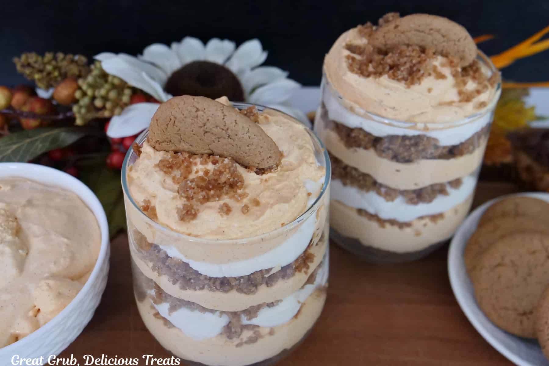 A wood surface with two pumpkin parfaits in glasses.
