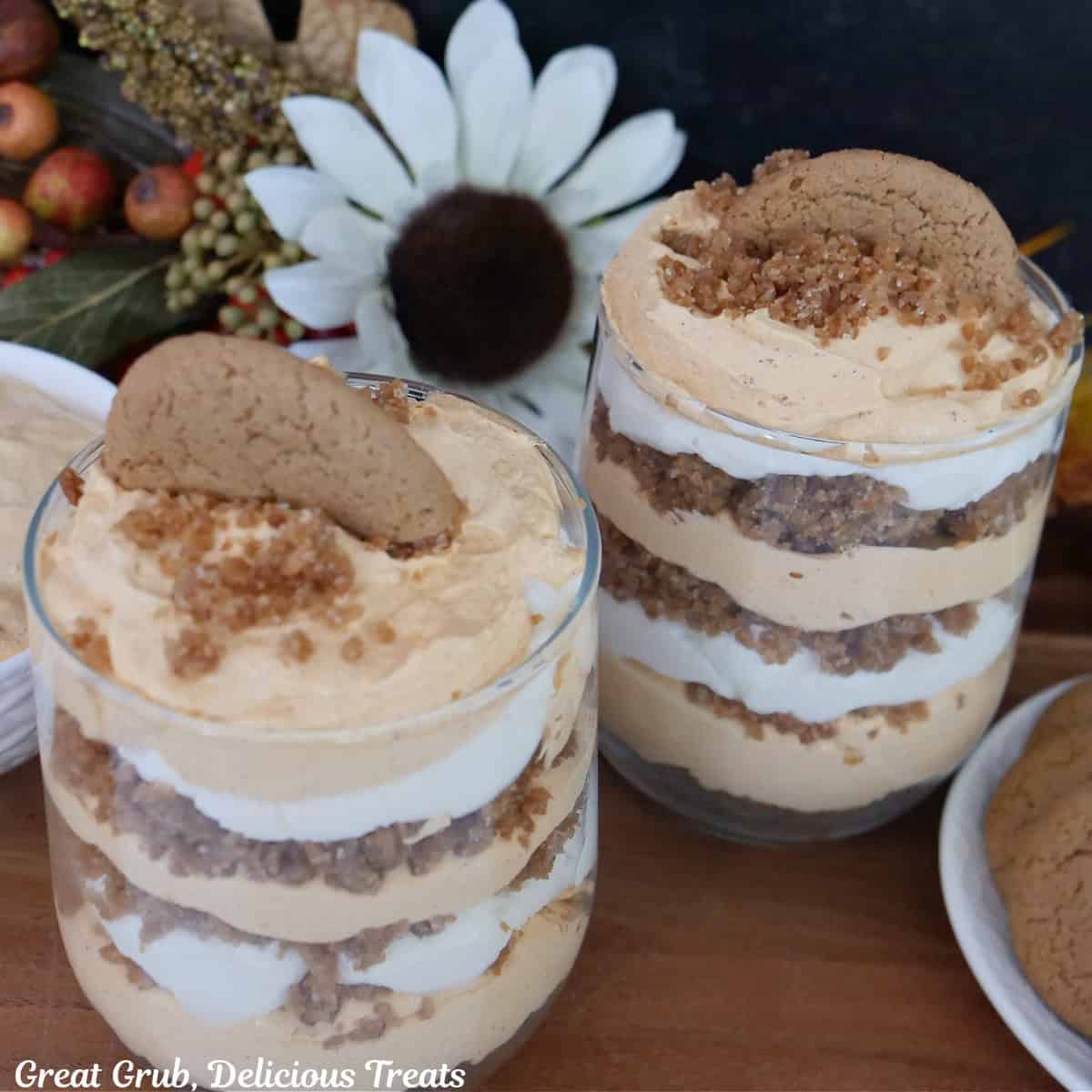 Two glass filled pumpkin mousse parfaits with fall foliage in the background.