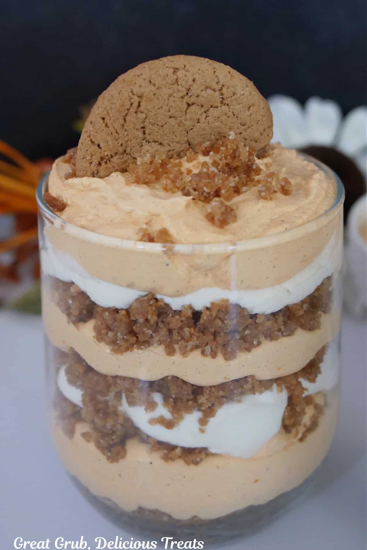 A white surface with a pumpkin parfait in a glass.